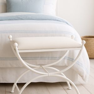 Banqueta de dormitorio Sevilla en blanco a los pies de una cama